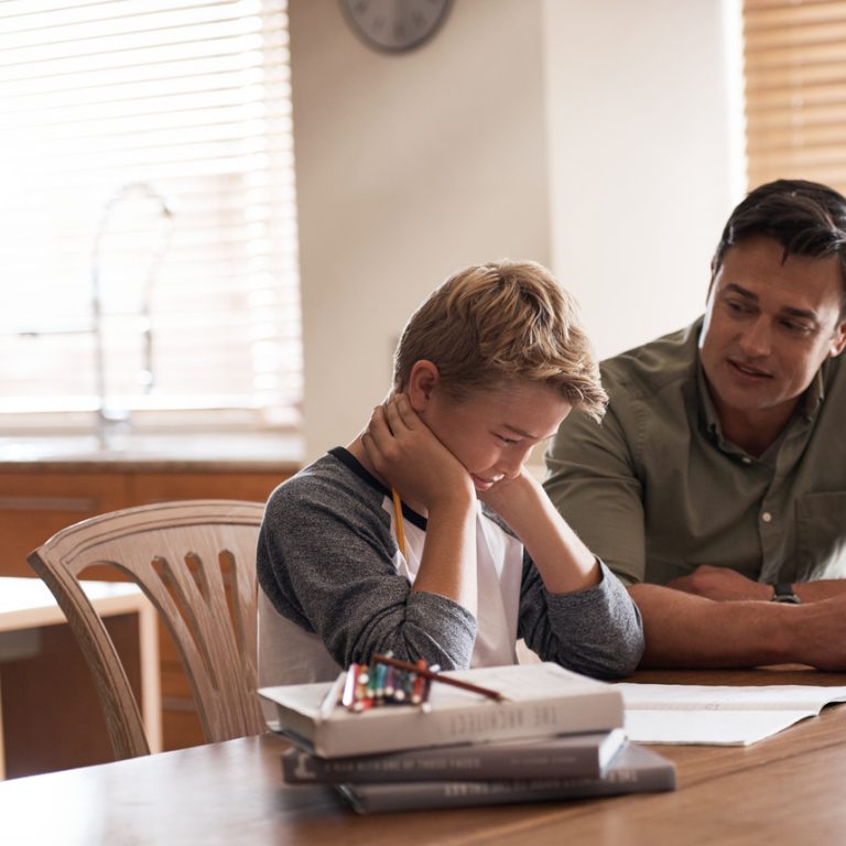 Shot of a father assisting his son with schoolwork at home