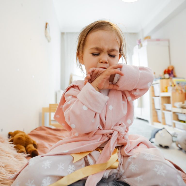 Sick 3 years old girl coughing in bed