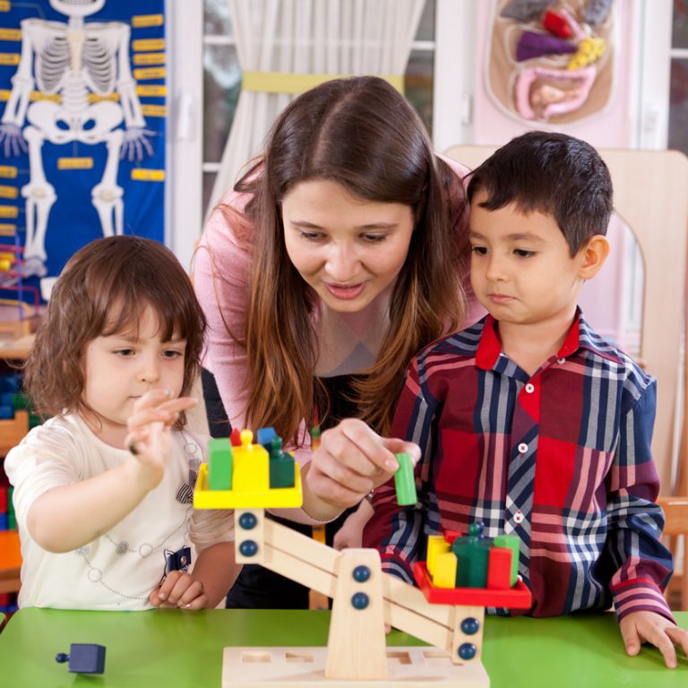 Preschooler and teacher playing with scale.